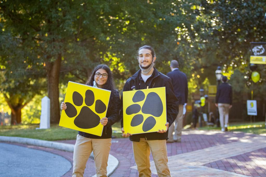 William and Zu hold up signs showing Wanda Wildcat's footprints